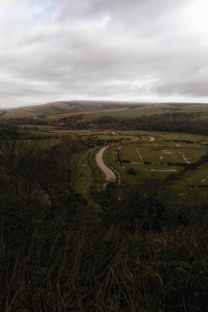 Gloomy shot of the river Cuckmere wandering up a misty valley
