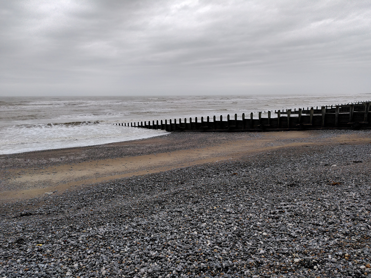 Wooden groynes on Eastbourne beach under an overcast sky