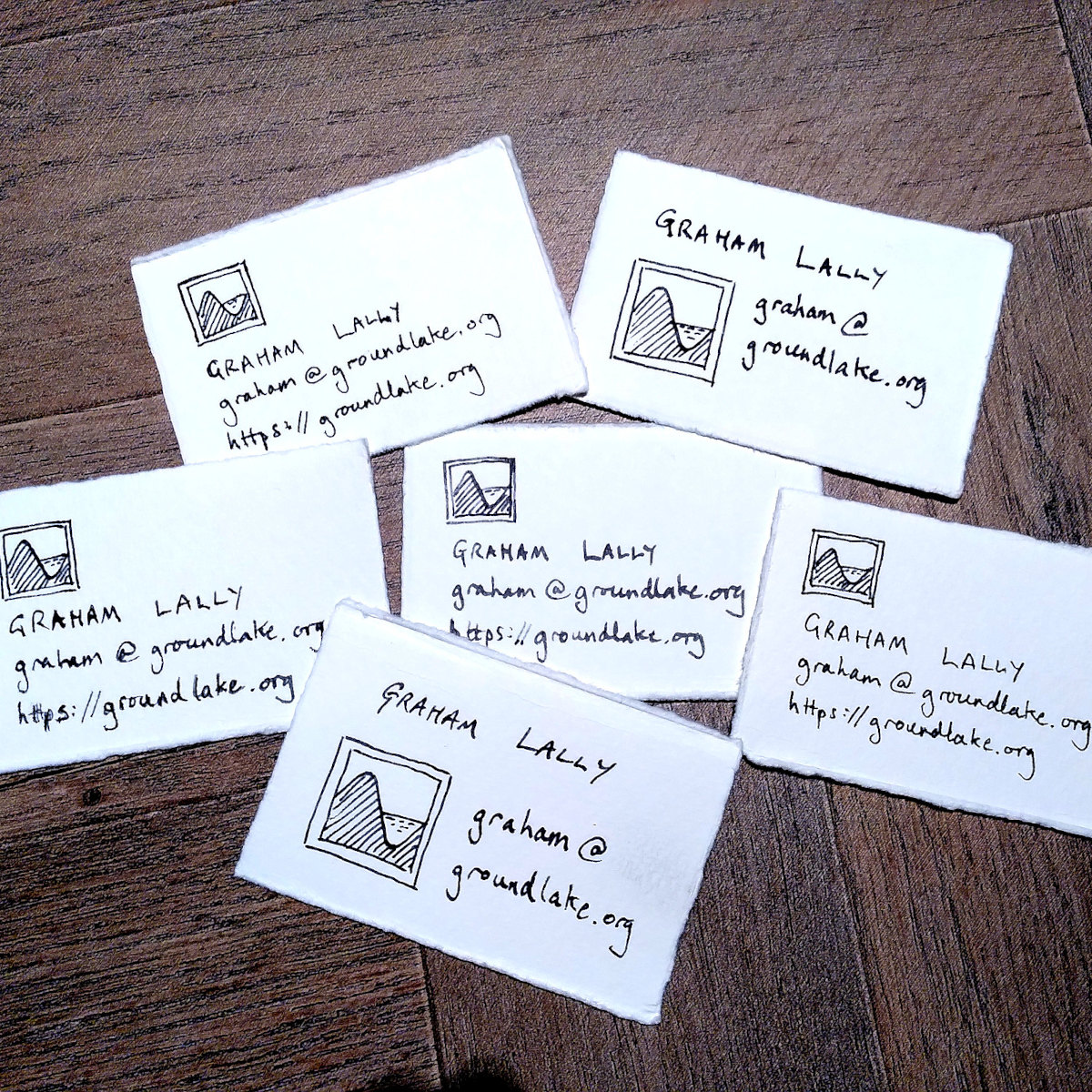 A small collection of handmade business cards, written with pen on torn out paper. Each card says 